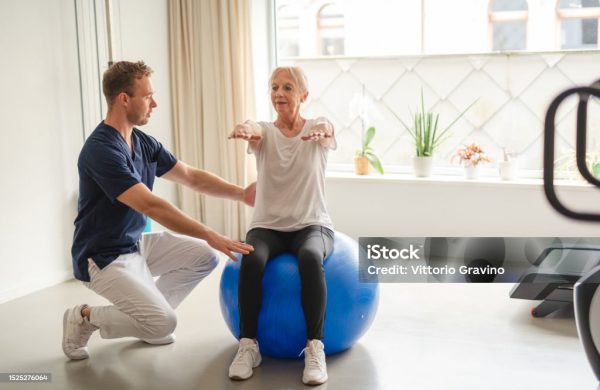 istockphoto-1525276064-1024×1024 A young physiotherapist guiding an elderly woman through rehabilitation exercises, empowering her on the path to wellness